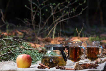 green tea beautifully brewed in a glass teapot outdoors in the forest with natural light with...
