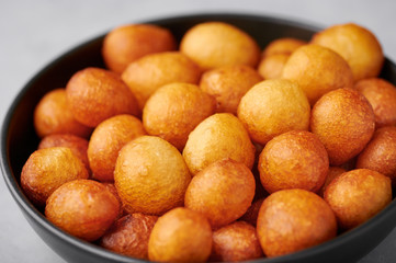 Loukoumades or luqaimat or lokma in black bowl. Loukoumades is an eastern cuisine donunts popular during Ramazan. Popular Ramadan Food. Iftar and Suhur sweets. Close up
