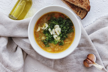 Lentil soup with garlic and herbs in a white bowl on the table. Diet, home-cooked food.