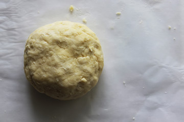A ball of dough lies on a white tablecloth on the table. Homemade cake. Housework.