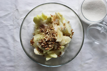 Apple slices with nuts in a large glass bowl. Apple pie filling. Homemade cake. Housework.