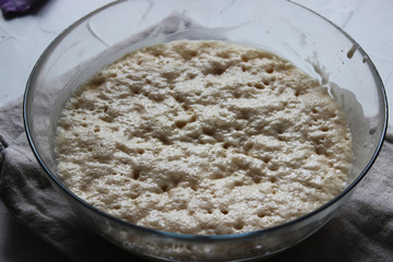 Yeast dough in a large glass bowl. Homemade cake. Concept of homework during the quarantine period.