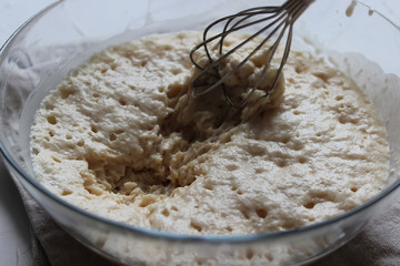 Batter with a whisk in a large glass bowl. Homemade cake. Concept of homework during the quarantine period.