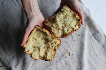 A broken cake with raisins in the hands of a girl. Homemade cake. Concept of homework during the quarantine period.