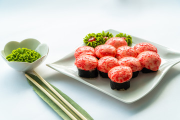 Red sushi on a white plate and white background with wasabi and chopstocks