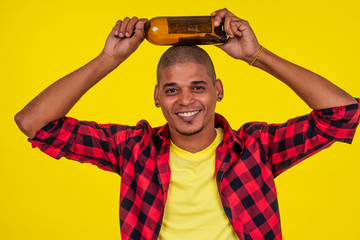 Fototapeta premium latin brazilian man holding alcohol bottle in studio yellow background
