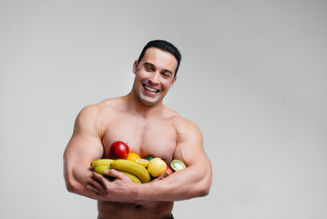 Sporty sexy guy posing on a white background with bright fruits. Diet. Healthy diet