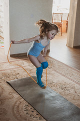 Little cute girl is practicing gymnastics at home. Online training. Quarantine. Stay at home.