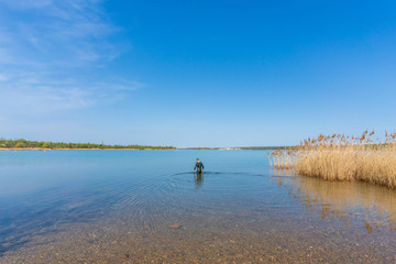 Triathlete in a wetsuit going into the water to have a swim in open water