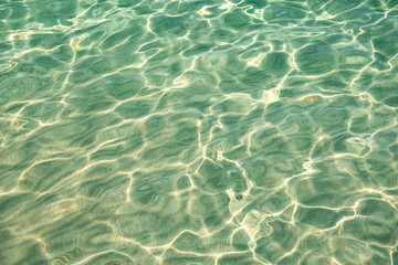 Sunlight reflections on the water surface at the flat sandy beach