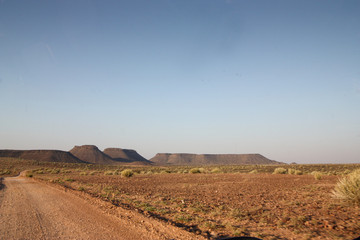 Dirt road in the desert with flat mountain on the horizon