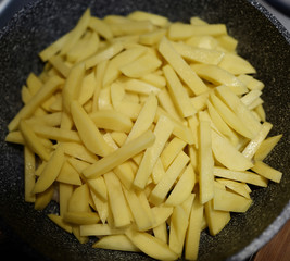 Raw chopped potatoes cooked for frying in a pan