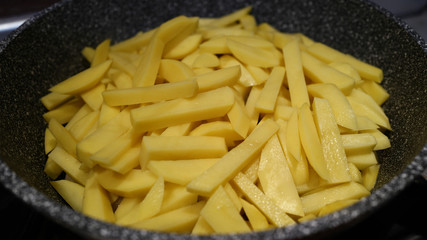 Raw chopped potatoes cooked for frying in a pan