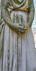 Detail of derelict folded female fingers of an ancient eroded white marble cemetary scuplture.
