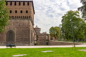 Fototapeta na wymiar Fragment of the fortress wall, the moat and corner tower of the Sforzesco Castle in Milan, Italy