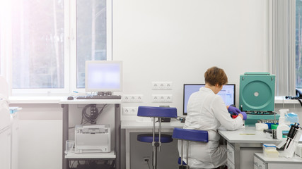Woman working in a laboratory on a modern machine for blood testing. Doctor checks the blood of the patients. Blood research in a modern scientific workplace.
