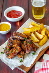 Pork ribs with potatoes on a wooden background. Barbecue. Grill. American cuisine. Recipe.