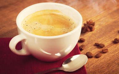 A cup of fresh coffee and coffee beans on the desk