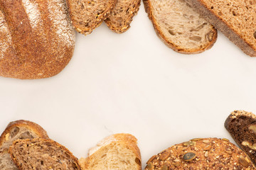 top view of fresh brown bread slices and loaves on white background