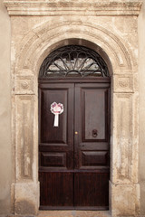 Fototapeta na wymiar Ancient wooden door of a historic building, with a pink bow that signals the birth of a baby girl