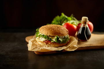 fresh tasty burger isolated on black wooden background with ingredients 