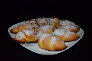 Homemade pastry. Bagel, Croissants in a white plate on a dark background.