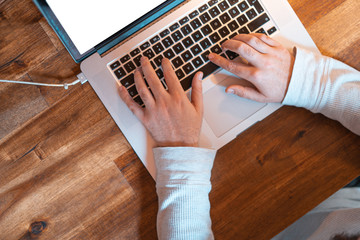 Hands pictured on the keyboard of a laptop typing something. 