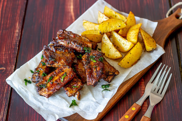 Pork ribs with potatoes on a wooden background. Barbecue. Grill. American cuisine. Recipe.
