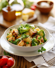 Pasta with grilled chicken, broccoli and green peas sprinkled with parmesan cheese and fresh herbs, close up