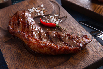 Ready striploin steak on a wooden panel.