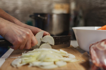 Hands of woman cutting onions on a wooden cutting board