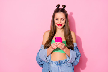 Photo of pretty millennial lady hold telephone hands texting boyfriend read love sms wear denim jacket green crop top naked belly denim shirt isolated pastel pink color background