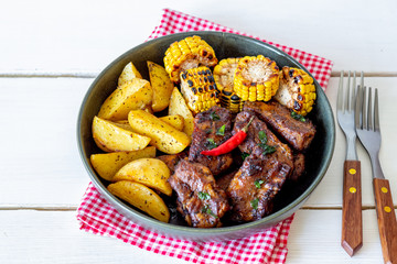 Pork ribs with potatoes on a wooden background. Barbecue. Grill. American cuisine. Recipe.