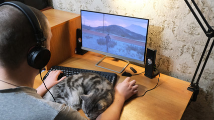 a gamer plays a game on a computer, a cat lies on a keyboard © Татьяна Грунт