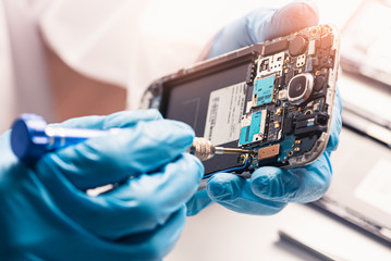 The asian technician repairing the smartphone's motherboard in the lab with copy space. the concept of computer hardware, mobile phone, electronic, repairing, upgrade and technology.