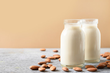 Fresh almond milk in glass bottle on beige. Close up.