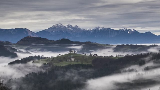 Zoom in time lapse of famous Saint Thomas church on hilltop with moving fog. In background Alps mountains. Amazing landscape nature in Slovenia. Well known spot for photographers all around the world