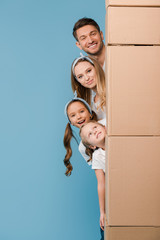 Fototapeta na wymiar happy parents and kids with cardboard boxes for relocation on blue