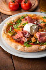 Deliziosa pizza primavera con prosciutto crudo, mozzarella fior di latte, rucola, sugo e pomodoro fresco