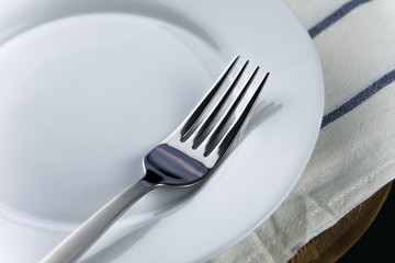 fork on a wooden table. Towel and plate.