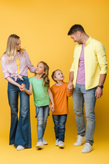 happy family holding hands with children on yellow