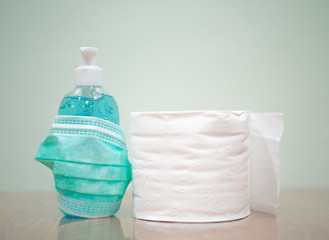 Alcohol gel,surgical mask and toilet paper on green tone.