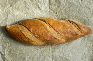 Fresh baked loaf bread on baking paper. Healthy, delicious and homemade food. Top view, flat lay.