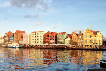 Obraz premium Willemstad/Curacao - Nov 15, 2016: The view of Willemstad harbour with colourful Dutch buildings in Curacao island. Bright reflection of beautiful houses in the water during sunny weather.
