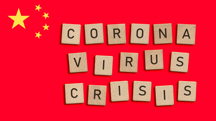 Corona virus crisis written with wooden tiles over Chinese flag background