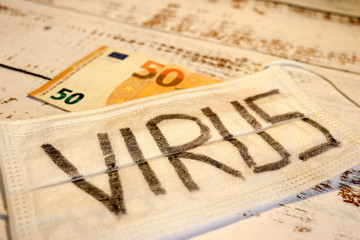 Crisis wallpaper new covid 2019 coronavirus strikes europe economy medical mask on a wooden background with the inscription virus with fifty euro banknote