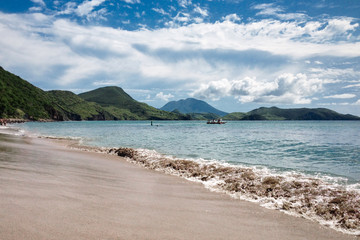 Fototapeta na wymiar St.Kitts Island/Saint Kitts and Nevis - Nov 29, 2016: Black sand beach view with mountains at the background. Beautiful travel picture.