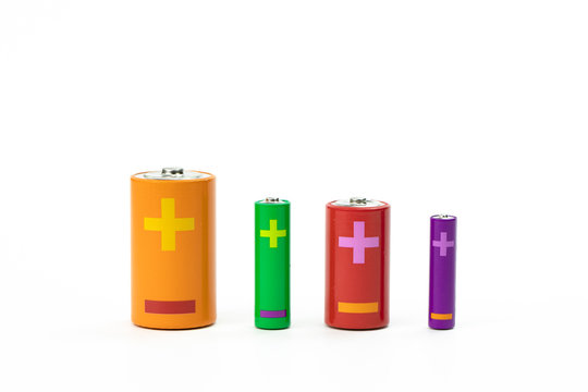 Four colorful batteries of different sizes isolated on white background. Recycling concept. Save environment. Cost, purchase or sale of electricity, high-capacity batteries