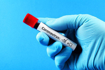 Obraz premium Coronavirus. Doctor's hand in a blue glove. Blood sample in vitro for analysis. Blue background.