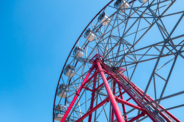 Ferris wheel on a background of clear blue sky. Bright sunny day. The concept of relaxation and entertainment.